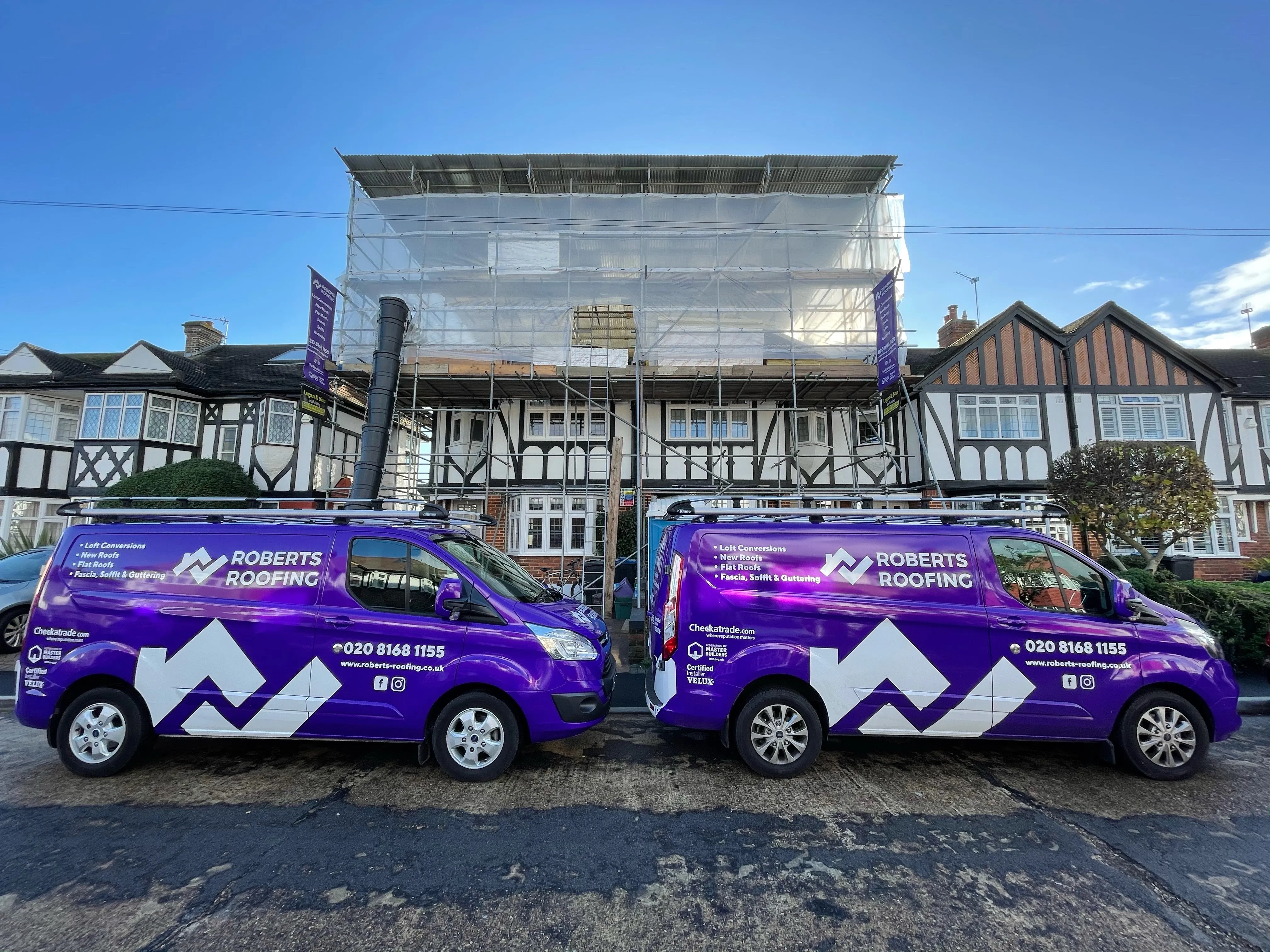 Two purple vans parked in front of a building.