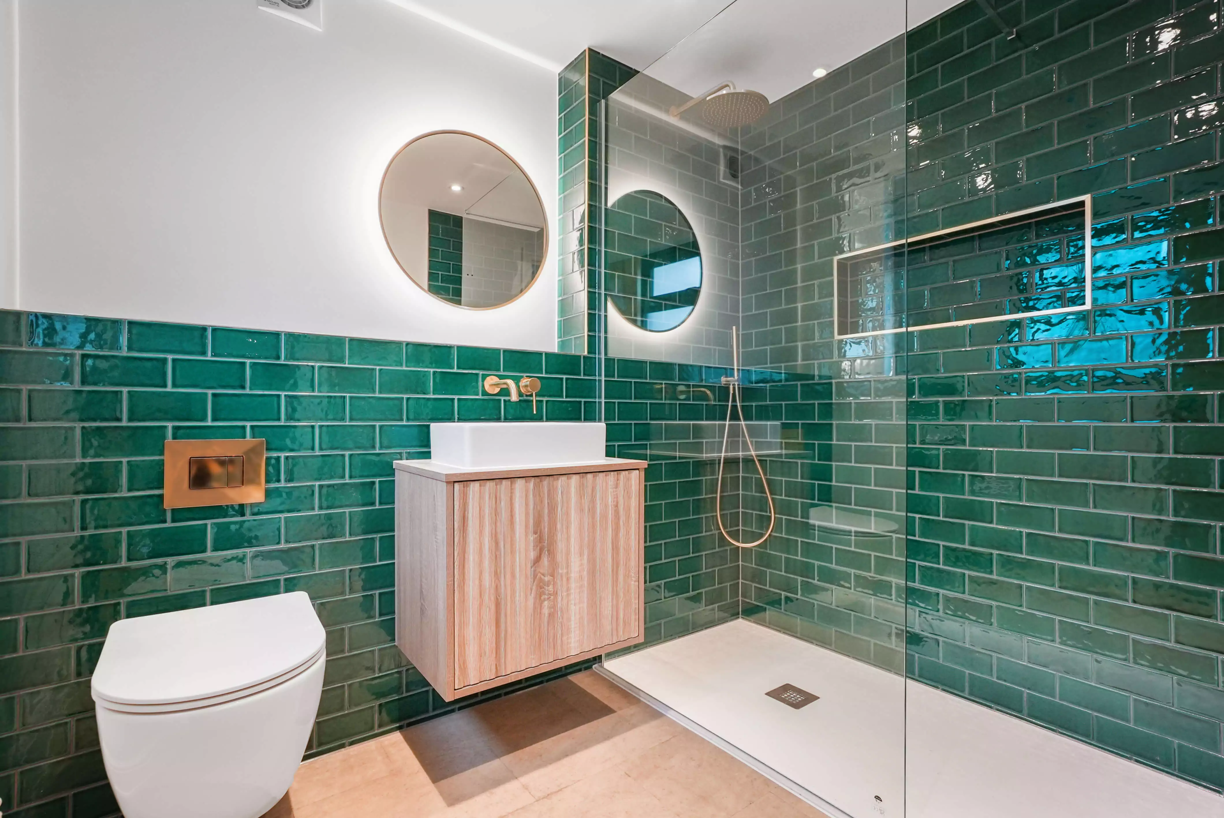 a bathroom with green tiles and a white toilet